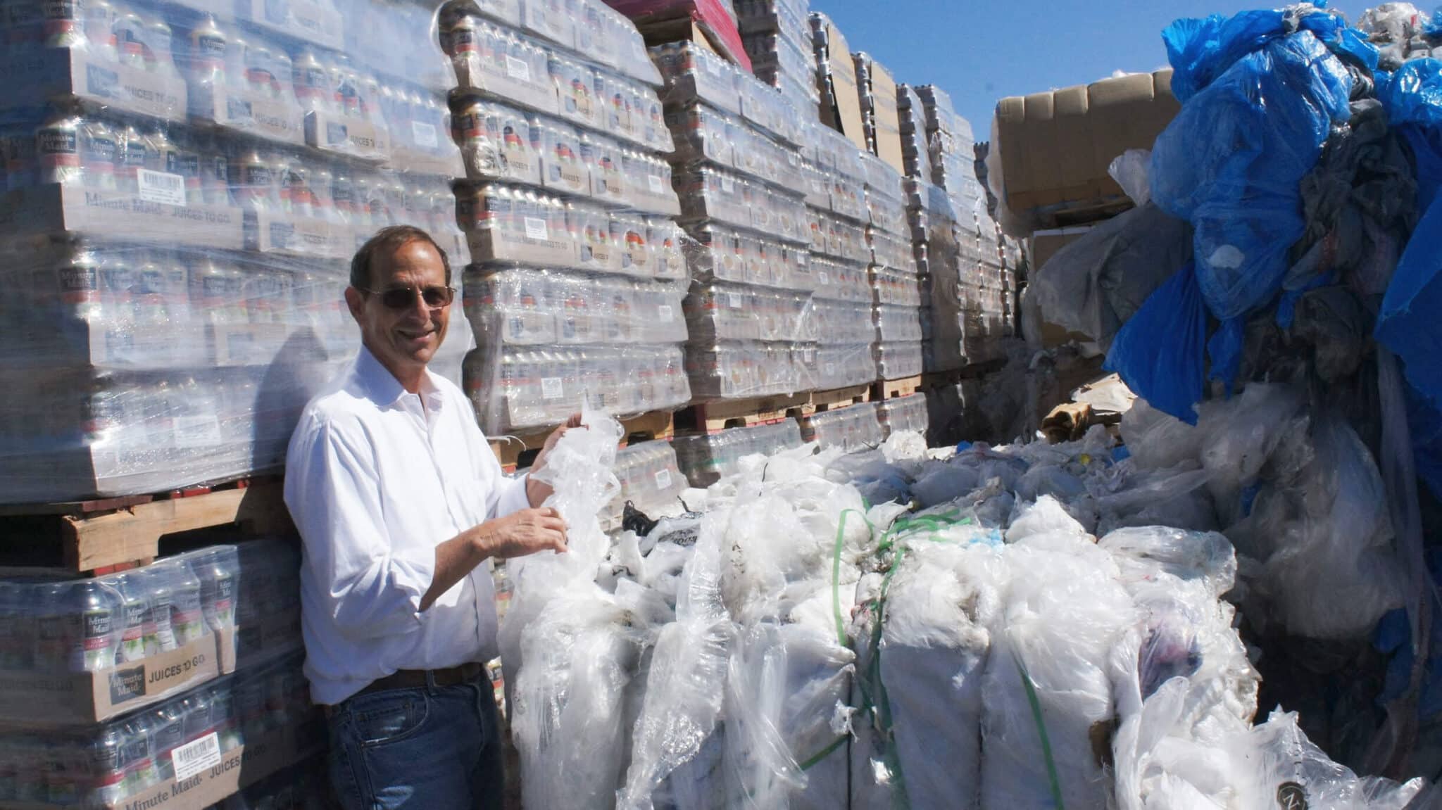 Steve Sutta in front of bulk palets of plastic bottles at recycling facility.
